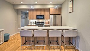 Uma cozinha moderna com uma ilha central, eletrodomésticos de aço inoxidável e banquetas.