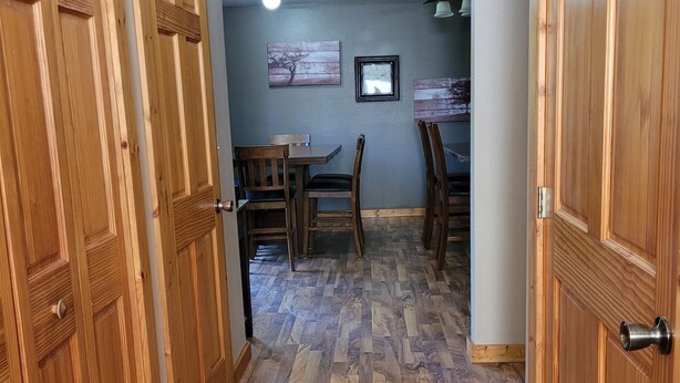 A hallway with wooden doors, a dining area with a table and chairs, and a ceiling light.
