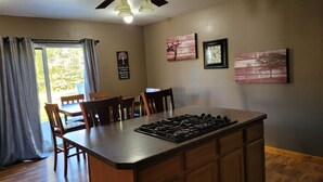 A kitchen with a central island, wooden chairs, a dining table, and a ceiling fan.