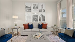 A living room with a sofa, two armchairs, a coffee table, and a wall with black and white cityscape photographs.
