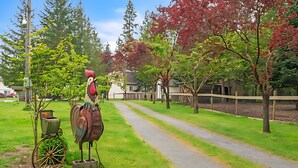 A rural pathway lined with trees and a large decorative rooster statue. - Charming 3-bedroom cottage in serene Enumclaw with AC (Enumclaw)