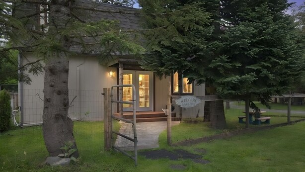 A house with a wooden deck, a fenced yard, and a welcome sign. - Charming 3-bedroom cottage in serene Enumclaw with AC (Enumclaw)