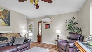 A living room with a sofa, armchair, and coffee table, a ceiling fan, and a large mirror. - Charming 3-bedroom cottage in serene Enumclaw with AC (Enumclaw)