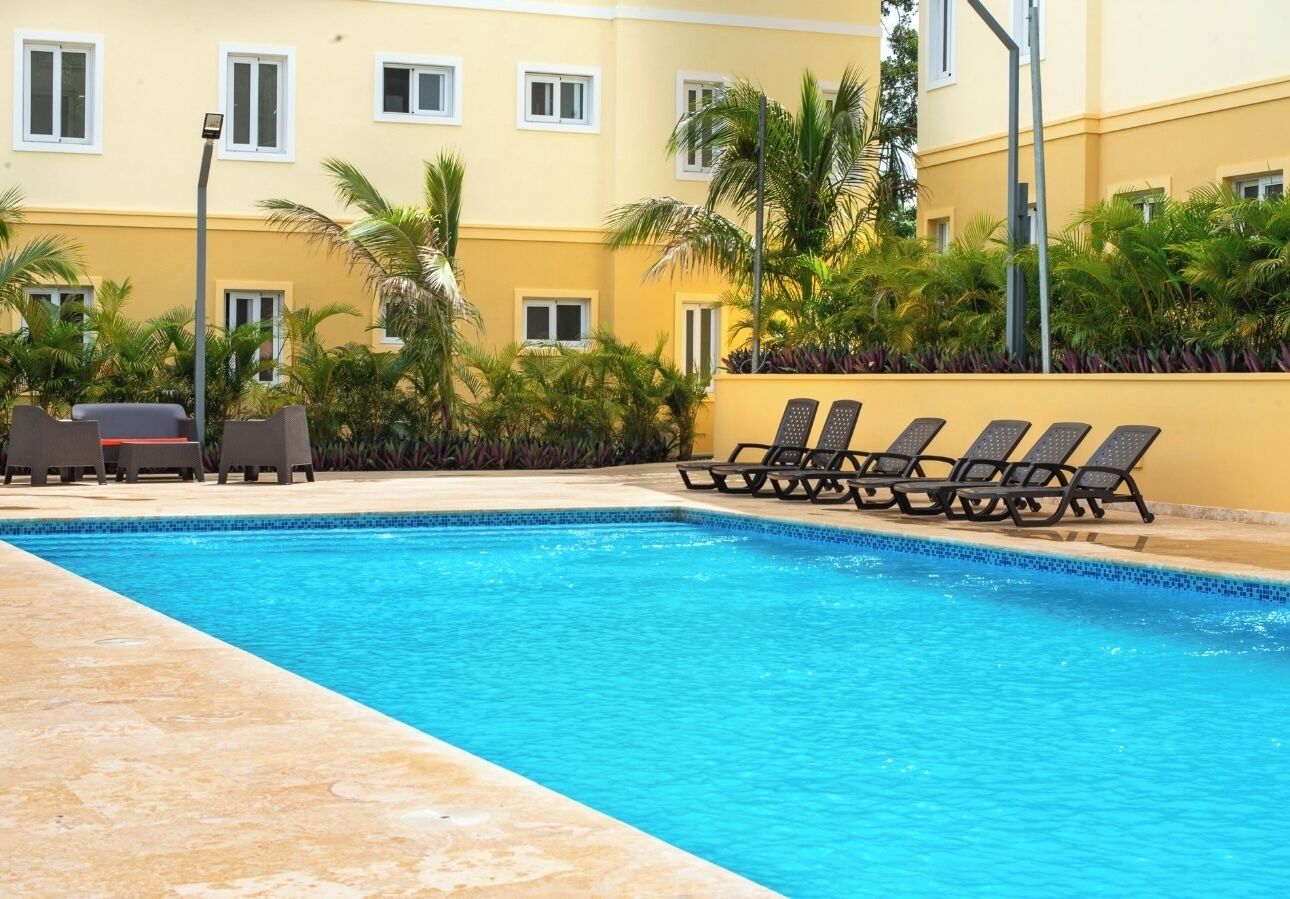 Une piscine avec des chaises longues et des palmiers.