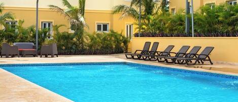 Une piscine avec des chaises longues et des palmiers.