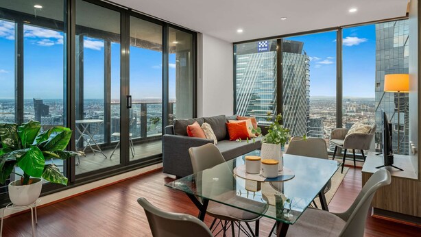 A modern living room with a glass table, comfortable seating, and a city view.