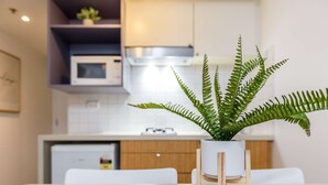 A modern kitchen with a microwave, a small refrigerator, and a potted fern on the counter.
