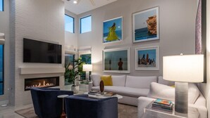 Una sala de estar moderna con chimenea, un televisor de pantalla plana y obras de arte en las paredes.