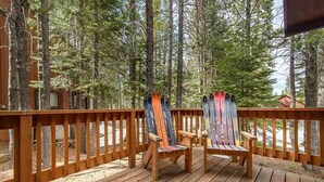 Una terraza de madera con dos sillas Adirondack y una barandilla de madera.