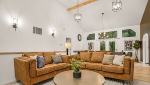 A modern living room with a sectional sofa, a round coffee table, and pendant lighting.