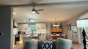 A modern kitchen with a dining area, a ceiling fan, and a view of the outdoors.