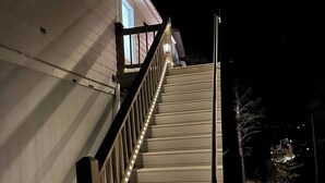A wooden staircase with railings leading to a white building at night.