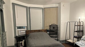 A bedroom with a bed, a desk with a computer, a chair, a fan, and a shelf. - Temple Hosp 2nd floor (Philadelphia)
