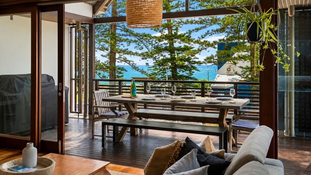 An outdoor dining area with a view of the sea, wooden furniture, and potted plants. - Luxury On The Bay 2 - Ocean Views (Byron Bay)