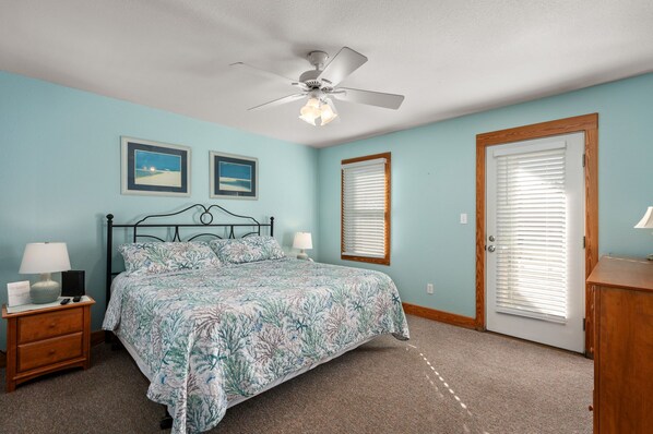A bedroom with a bed, nightstand, lamp, ceiling fan, and two framed pictures on the wall.