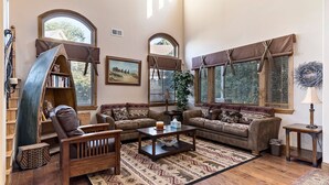 A spacious living room with a large bookshelf, two sofas, a coffee table, and a patterned rug. - Charming 4-bedroom chalet with AC and WiFi in gorgeous Lake Arrowhead (Lake Arrowhead)