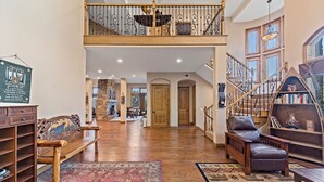 A spacious interior with a wooden staircase, a fireplace, and a high ceiling. - Charming 4-bedroom chalet with AC and WiFi in gorgeous Lake Arrowhead (Lake Arrowhead)