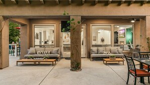 A modern outdoor living space with two sofas, a coffee table, and a dining table. - Rare Gem: Pool, Spa, Game Room, Fire Table! (Indio)