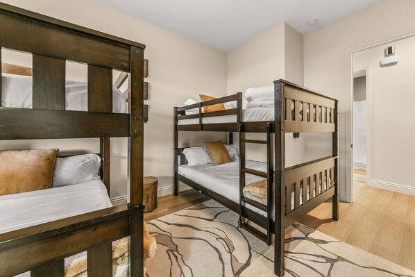 Habitación con literas, cabecera de madera, una mesita redonda y una alfombra estampada.