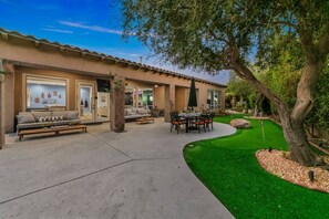 A residential property with a patio, outdoor seating, a lawn, and a tree.