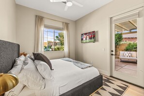 Ein Hotelzimmer mit Bett, Fernseher an der Wand und Blick auf die Terrasse.