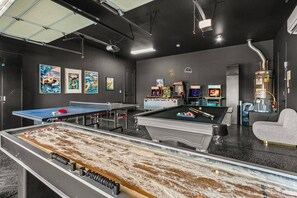 A billiards room with a pool table, foosball table, and various arcade games.