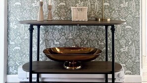 A room with a dark wooden console table, a large mirror, a lamp, and a decorative bowl on the table. - Charming Condo Retreat (Welches)