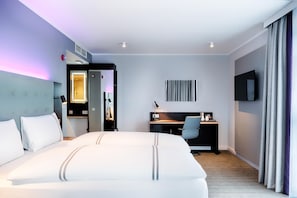 Relax in a spacious room with a large bed, desk, and flat-screen TV.