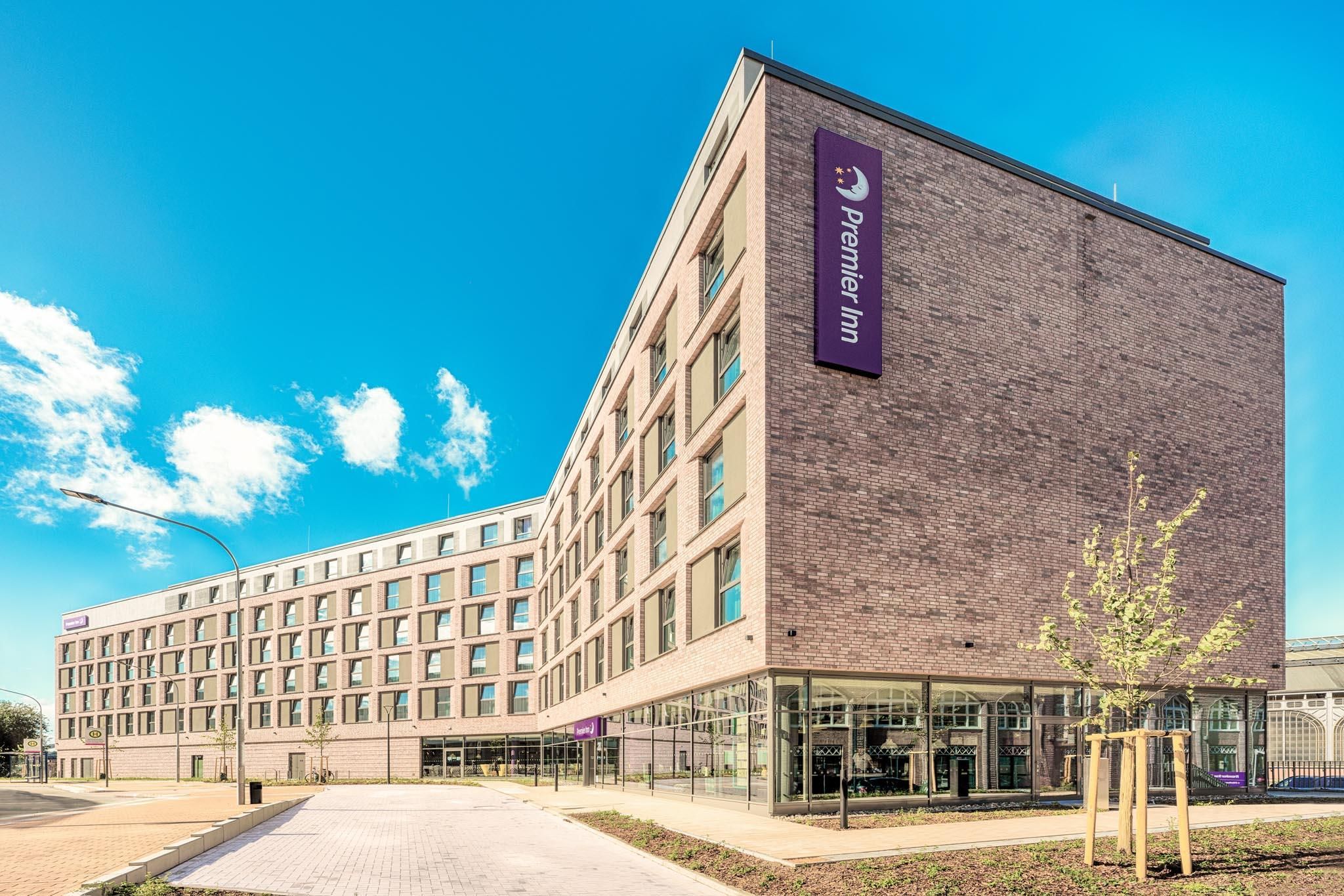 Een hotel met een gevel van baksteen, een glazen ingang en een helderblauwe lucht.
