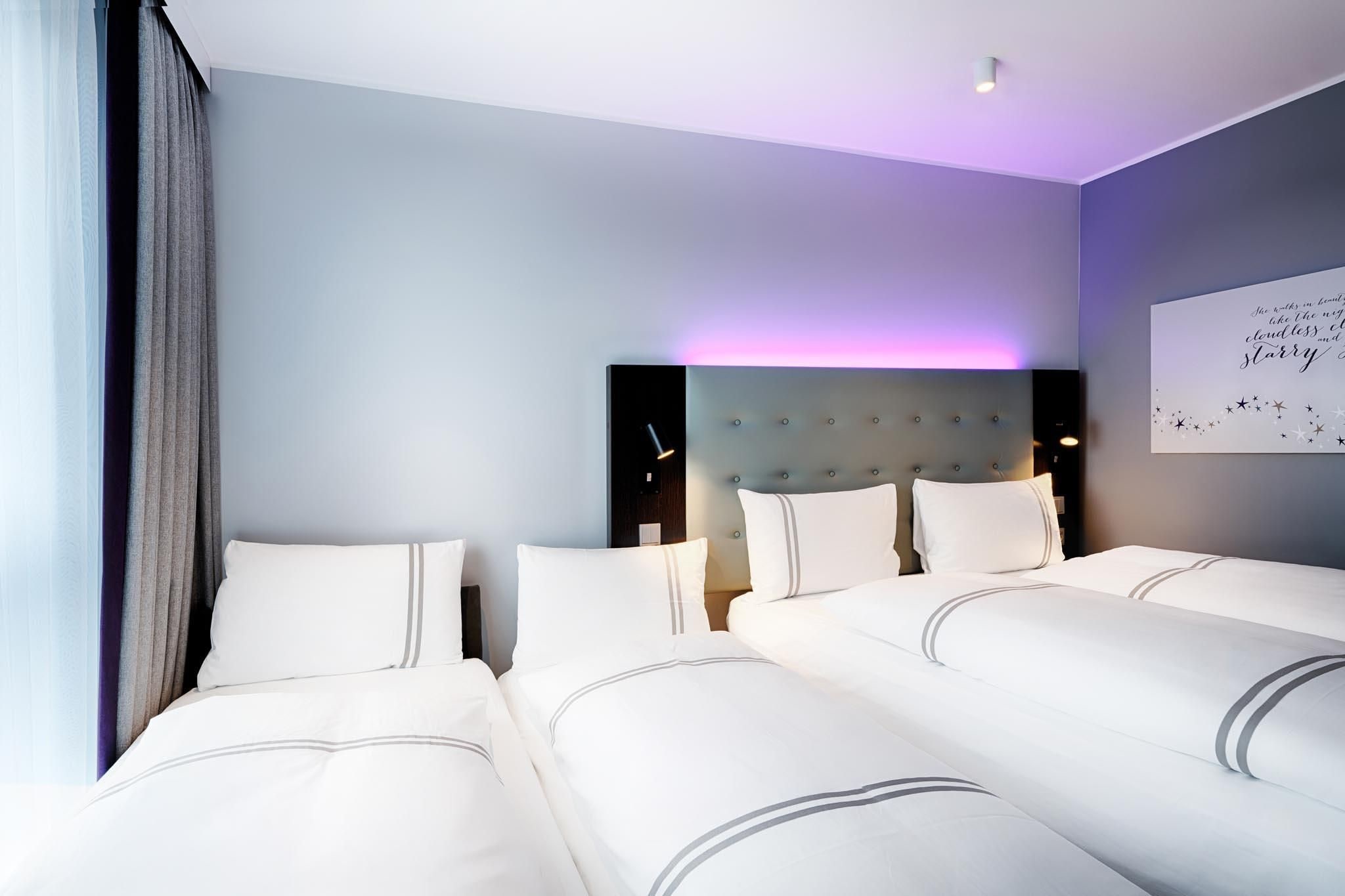 A hotel room with a large bed, a headboard, and a wall with a decorative sign.