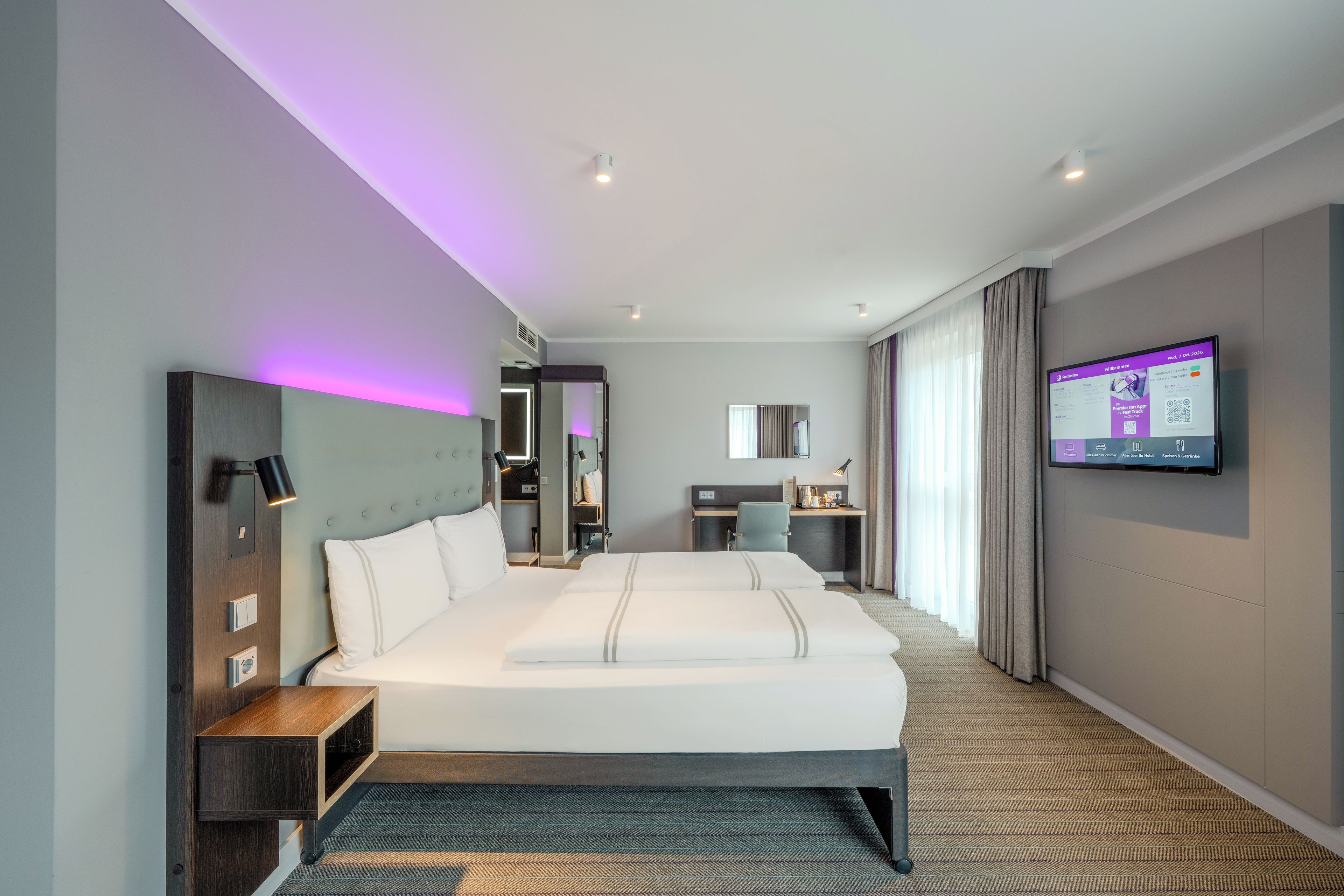 Una habitación de hotel moderna con una cama grande, un escritorio y una televisión.