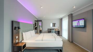 Una habitación de hotel moderna con una cama grande, un escritorio y una televisión.