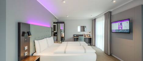 Una habitación de hotel moderna con una cama grande, un escritorio y una televisión.