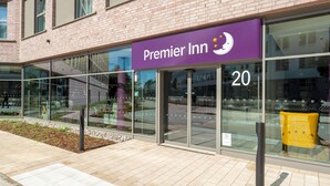 Un hotel Premier Inn con un letrero morado, ventanas grandes y fachada de ladrillo.