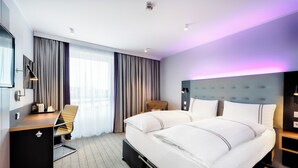 A modern hotel room with a large bed, a desk, and a chair. - Premier Inn Lübeck City Centre (Lubeck)