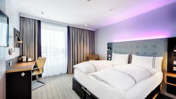 Una habitación de hotel moderna con una cama grande, un escritorio y una silla.