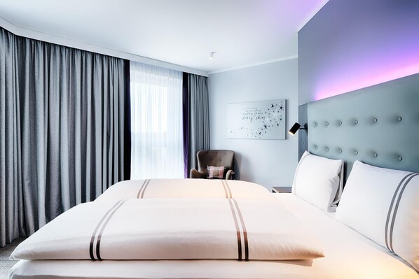 A hotel room with a large bed, a chair, a headboard, and a wall-mounted artwork. - Premier Inn Lübeck City Centre (Lubeck)
