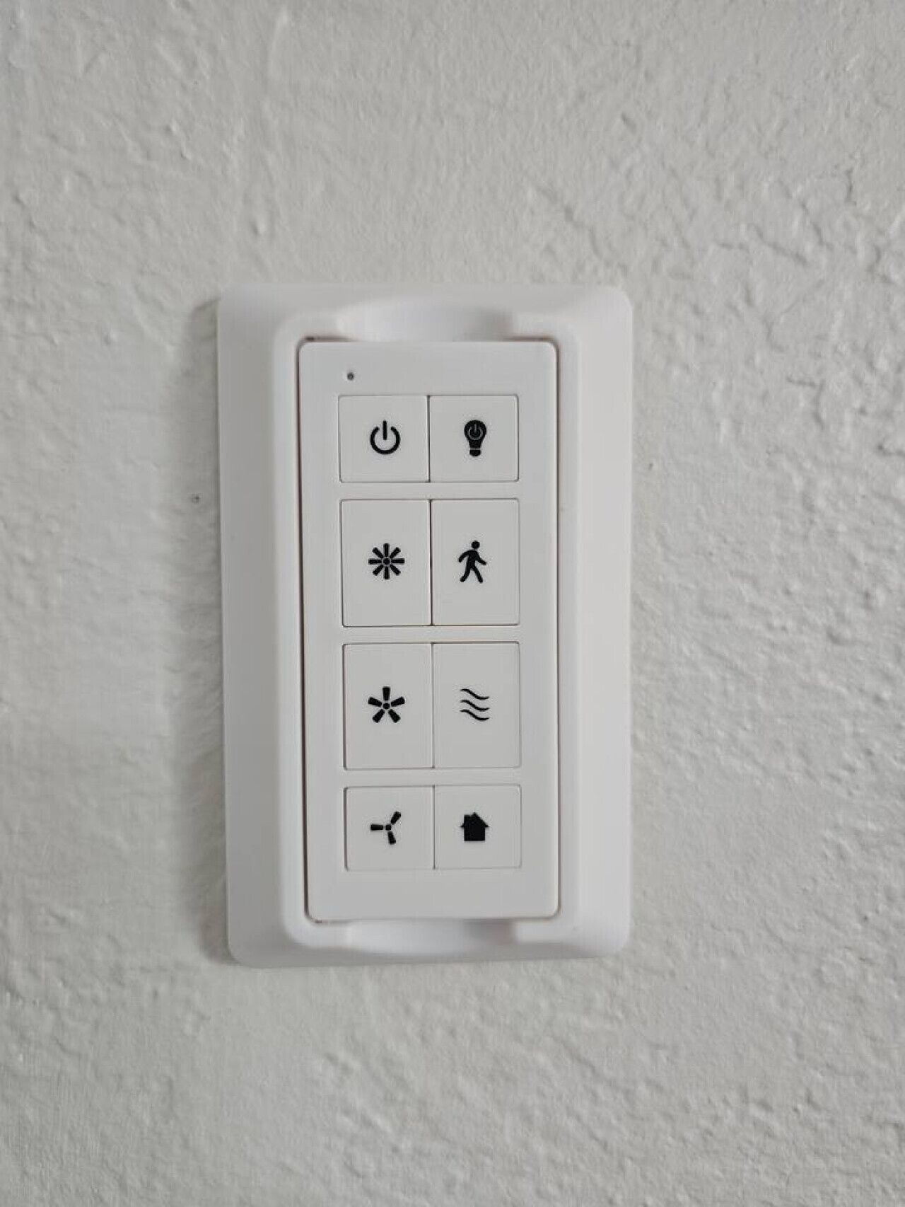 Un panel de control blanco instalado en la pared con varios símbolos.