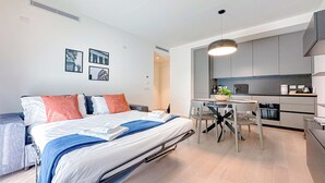 Una habitación de hotel moderna con una cama, una pequeña mesa de comedor y una kitchenette.