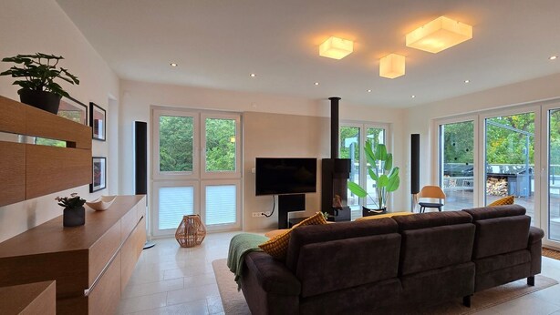 A modern living room with a sofa, TV, and large windows.