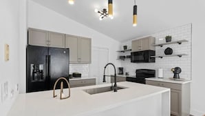 Een moderne keuken met een centraal eiland, witte kastjes en zwarte apparatuur.