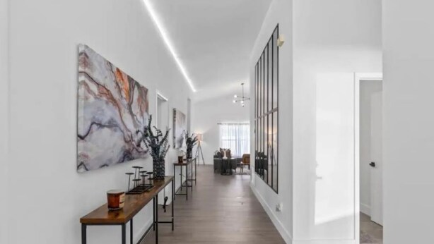 Een modern interieur met een lange gang, houten vloeren en een eetgedeelte met een lange tafel en stoelen.