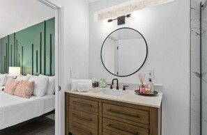 Una camera d'albergo moderna con un letto, una toeletta con specchio e un comodino.