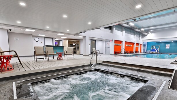An indoor swimming pool with a hot tub, seating area, and a reception desk.