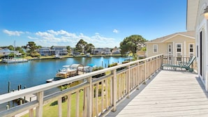 A wooden deck with a railing overlooking a calm lake, surrounded by houses and boats. - 5534 Life of Reilly * Canalfront * Dock (Kill Devil Hills)