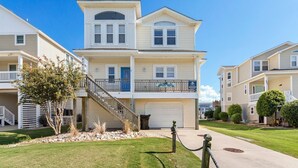 A two-story residential building with a front porch, a garage, and a staircase leading to the upper level. - 5534 Life of Reilly * Canalfront * Dock (Kill Devil Hills)