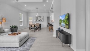 A modern living room with a sofa, dining area, and TV.