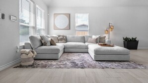 A modern living room with a sectional sofa, a large abstract painting, and a floor lamp.