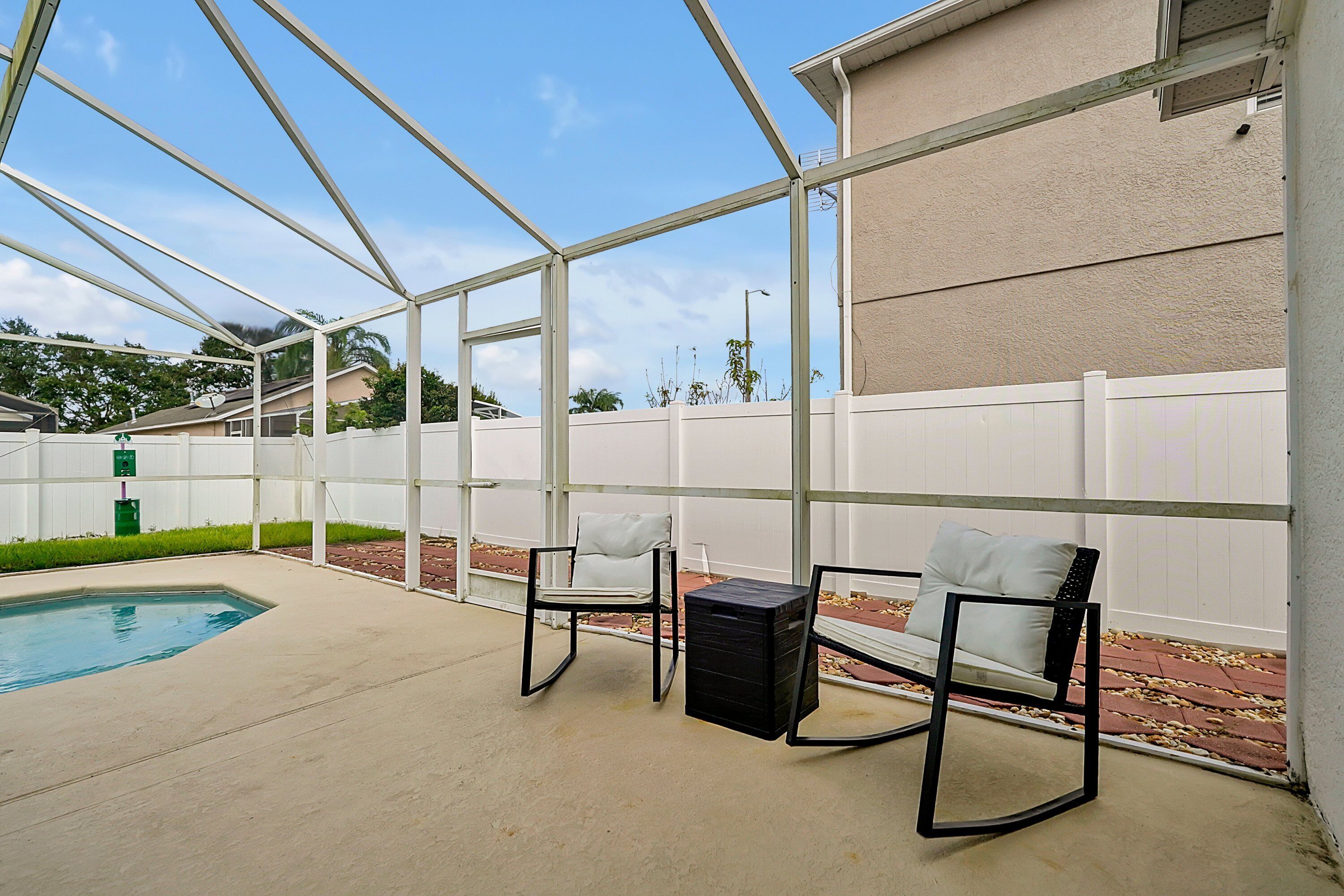 Une terrasse extérieure avec une piscine, deux chaises et une petite table.
