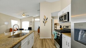 A modern kitchen with granite countertops, stainless steel appliances, and white cabinetry. - Family & Pet-Friendly Pool Home | Near Disney (Davenport)